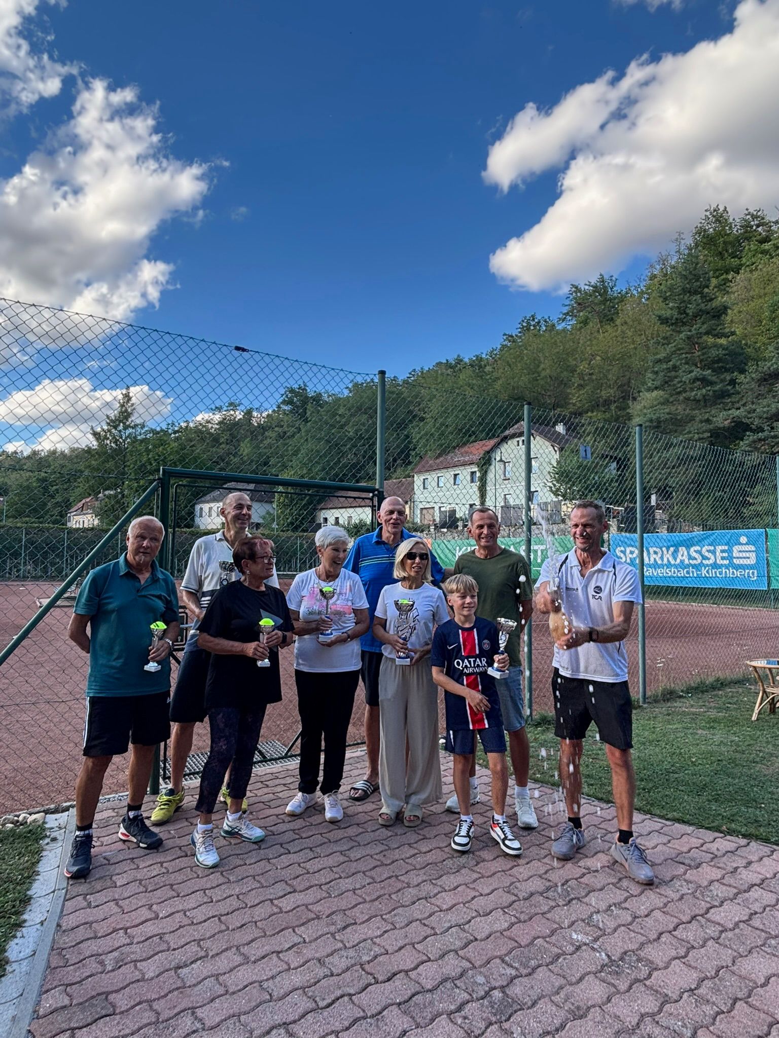 Siegerehrung mit Pokalen und Sektdusche auf der Tennisanlage